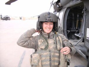Photo of Sarah Doran in military fatigues by helicopter
